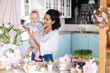 Mutlu genç anne ve küçük kızı mutfakta bir fincan çayla.