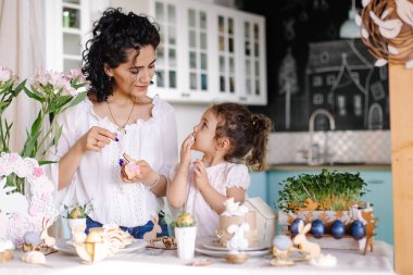 Güzel genç anne ve kızı doğum günü pastasını süslüyorlar.
