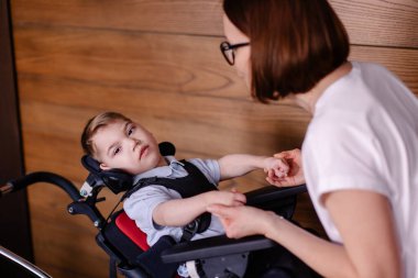 Özel tekerlekli sandalyedeki güzel çocuk. Annesiyle beyin felci geçiren bir çocuk. Öğretmenle rehabilitasyon bir süreçtir. Yaşam tarzı anları. Rehabilitasyon terapisti ders terapisi. arz