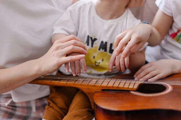 Serebral felçli bir çocuğun elleri. Müzik rehabilitasyonu. Müzik aleti gitar telleri. Titreşim sesleri. Özürlülerle dersler