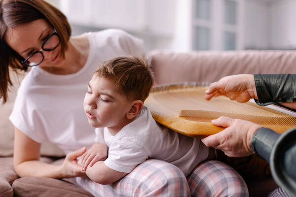 Занимается ребенок с церебральным параличом. Реабилитация инвалида с музыкой. Арт терапия. Реабилитационный терапевт музыкант играет на арфе. Ощущение тактильной вибрации. Ребенок с аутизмом 