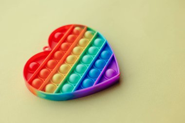 Çocuklar için yeni moda bir oyuncak. Anti-stres parmak baloncukları popüler oldu. Gökkuşağı rengi kalp şeklinde silikon poppit. Rahatlama basit gamzesi. Boşluk üst görünümü renkli arkaplanı kopyala. 