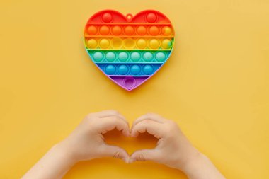 Çocuklar için yeni moda bir oyuncak. Anti-stres parmak baloncukları popüler oldu. Gökkuşağı rengi kalp şeklinde silikon poppit. Rahatlama basit gamzesi. Boşluk üst görünümü renkli arkaplanı kopyala. 