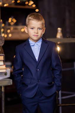 Mavi takım elbiseli bir çocuk. Okul üniforması. Okuldaki bir öğrenci. Birinci sınıf öğrencisi okula hazırlanıyor. Eğitimsel süreç. Küçük iş adamı. Kendinden emin duruş
