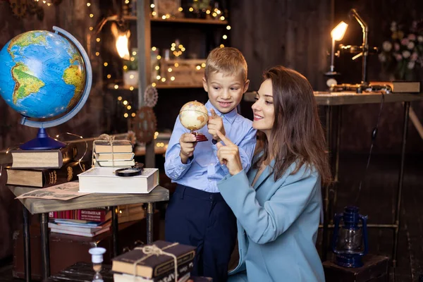 A good kind Teacher teaches a student. Mother shows her son a globe. Studying geography in elementary school. Science classroom. Support from a friendly tutor. Back to school concept