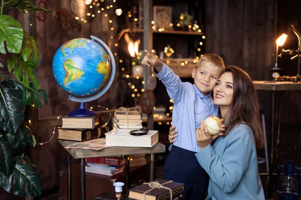 good kind Teacher teaches a student. Mother shows her son a globe. Studying geography in elementary school. Science classroom. Support from friendly tutor. Back to school concept. forward to knowledge