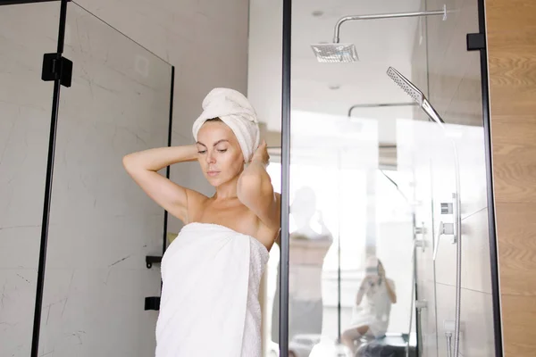 woman comes out of the bathroom. Early morning. Invigorating shower. Daily routine. beginning of day is charge of positive mood. White towel on head. Portrait of a smiling girl. Relaxation after work