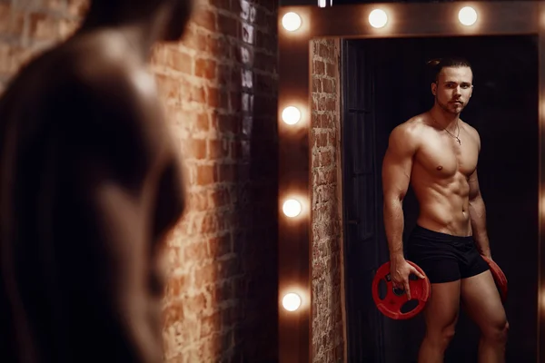 Young muscular man and mirror — Stock Photo, Image