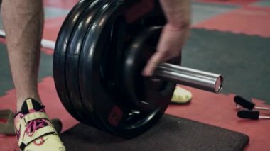Spor salonunda ağırlık kaldıran genç bir halterci, ağır çekimde.