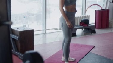 Spor salonundaki genç, formda kadın ağır çekimde çalışıyor.