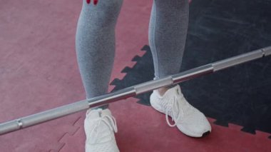 Spor salonunda halterle çalışan sağlıklı genç bir kadın, ağır çekimde.