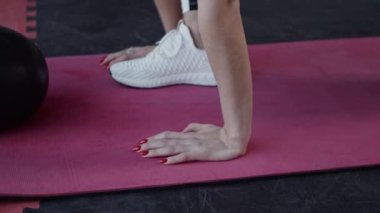 Spor salonundaki genç, formda kadın ağır çekimde çalışıyor.