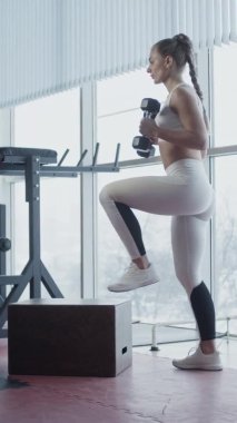 Spor salonundaki genç, formda kadın, ağır çekimde. Dikey video