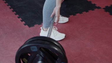 Spor salonunda halterle çalışan sağlıklı genç bir kadın, ağır çekimde.