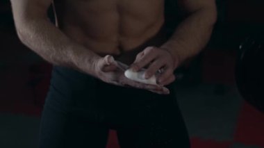 Spor salonundaki genç kaldırıcı ellerine tebeşir uyguluyor. Yavaş çekim