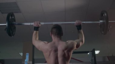 Jimnastik salonundaki genç kaldırıcı bileşik hareketler yapıyor. Omuz presi. Yavaş çekim