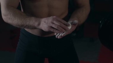 Spor salonundaki genç kaldırıcı ellerine tebeşir uyguluyor. Yavaş çekim