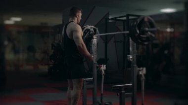 Jimnastik salonundaki genç kaldırıcı bileşik hareketler yapıyor. Çömel. Yavaş çekim