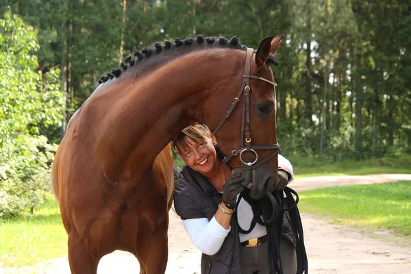 Idosos mulher feliz e cavalo marrom na floresta — Fotografia de Stock