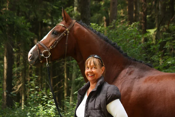 Elderly woman and brown horse portrait in the forest — Stock Photo, Image