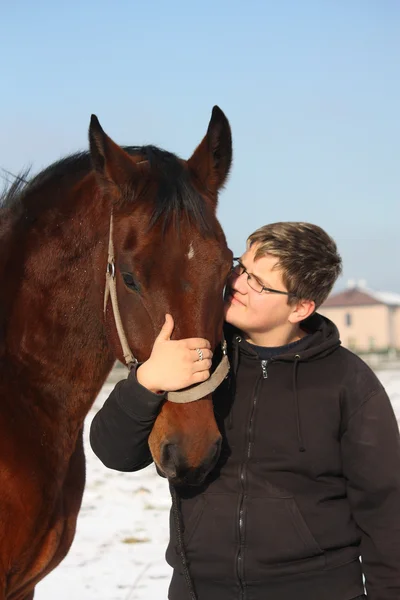 Teenager boy and bay horse portrait in winter — Stock Photo, Image