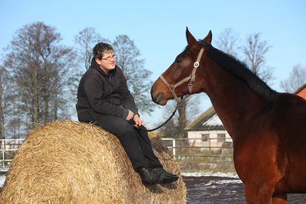 干し草のベールと湾の馬で休んでティーンエイ ジャーの男の子 — ストック写真