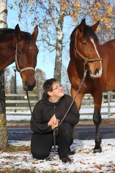 Ragazzo adolescente e due cavalli marroni — Foto Stock
