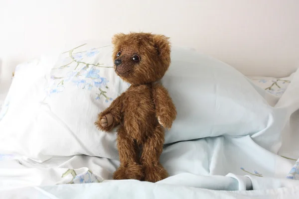 Cute brown teddy bear resting on the bed — Stock Photo, Image