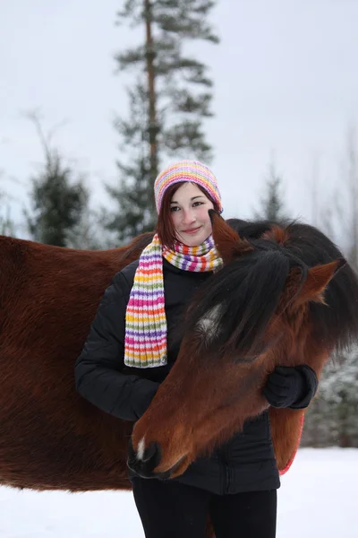 Bella ragazza adolescente che abbraccia cavallo marrone in inverno — Foto Stock