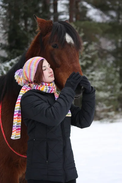 Beautiful teenager girl hugging brown horse in winter — Stock Photo, Image