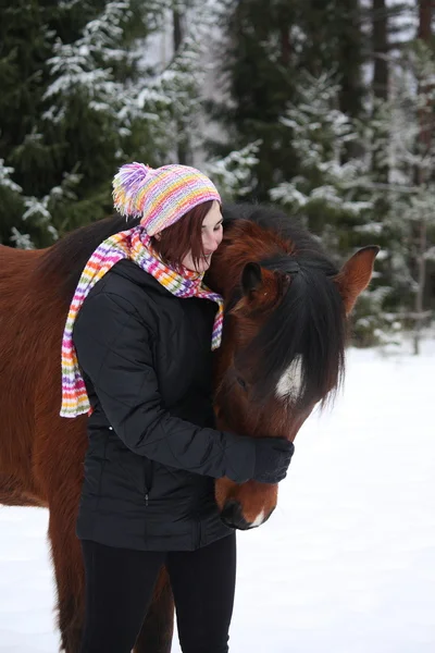 Beautiful teenager girl hugging brown horse in winter — Stock Photo, Image