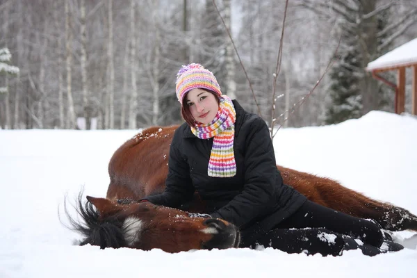 Teenager girl and brown horse lying in the snow — Stock Photo, Image