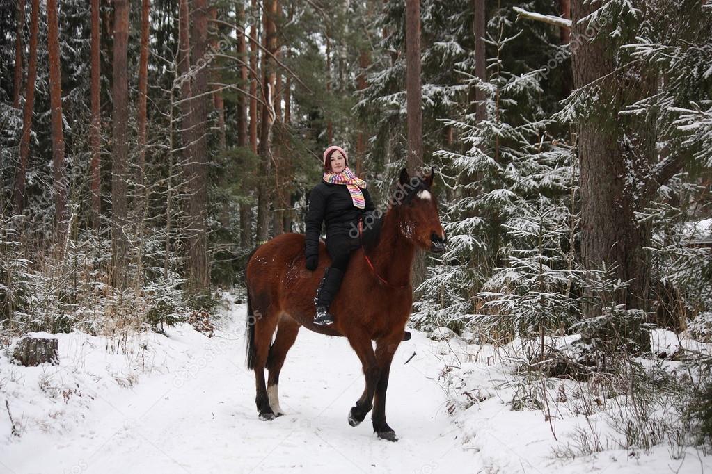 Beautiful teenager girl riding brown horse in the forest