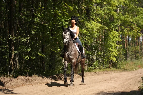 Vacker kvinna ridning grå häst i skogen — Stockfoto