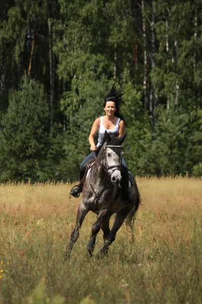 Beautiful woman riding gray horse in the forest — Stock Photo, Image