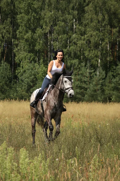 Beautiful woman riding gray horse in the forest — Stock Photo, Image