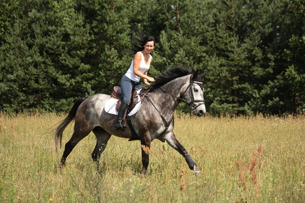 Красивая женщина верхом на серой лошади в лесу
