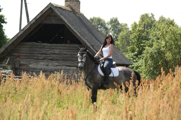Retrato de una hermosa mujer a caballo cerca del granero —  Fotos de Stock