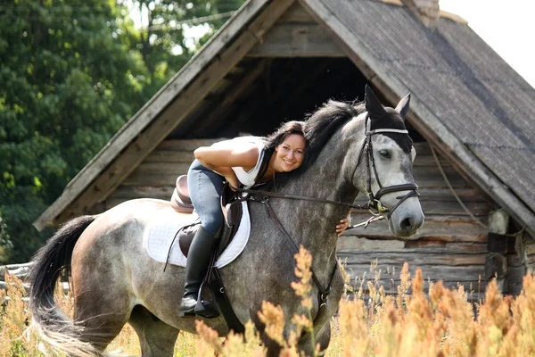 Portrait of beautiful woman on horse near the barn Stock Picture
