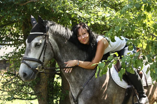 Портрет красивой женщины и серой лошади в саду — стоковое фото