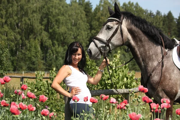 Vacker kvinna i den blommande trädgården med häst — Stockfoto