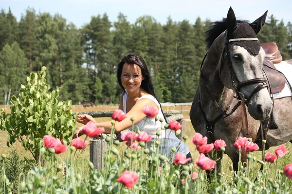 Hermosa mujer en el jardín floreciente con caballo — Foto de Stock