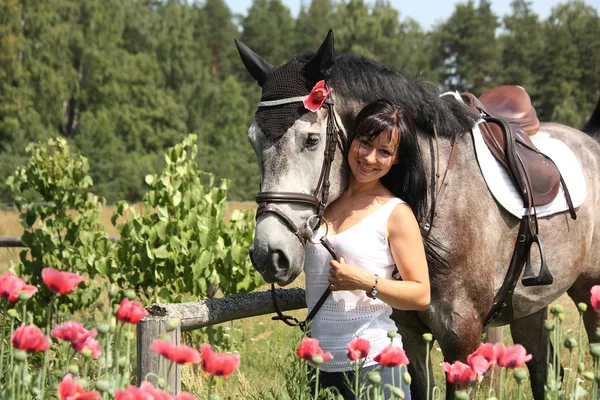 Vacker kvinna i den blommande trädgården med häst — Stockfoto