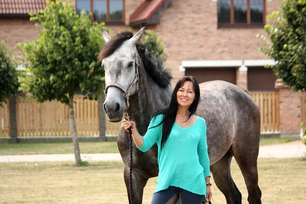 Bella giovane donna e cavallo vicino cottage — Foto Stock