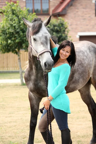 Bella giovane donna e cavallo vicino cottage — Foto Stock