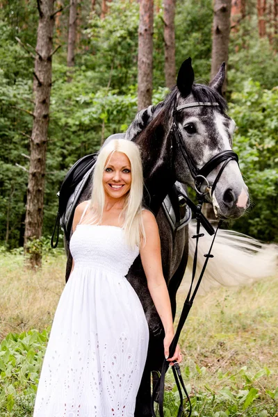 Bella donna bionda e cavallo grigio nella foresta — Foto Stock