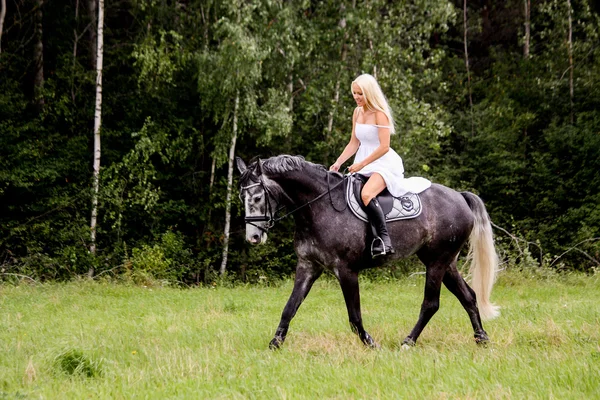 Beautiful blonde woman and gray horse riding — Stock Photo, Image