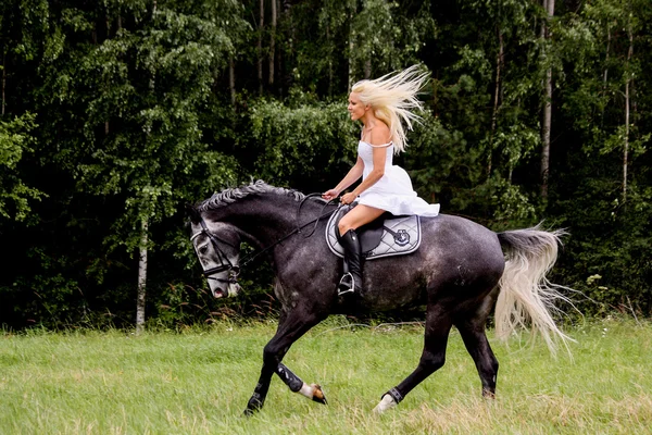 Krásná světlovlasá žena a šedé na koni — Stock fotografie