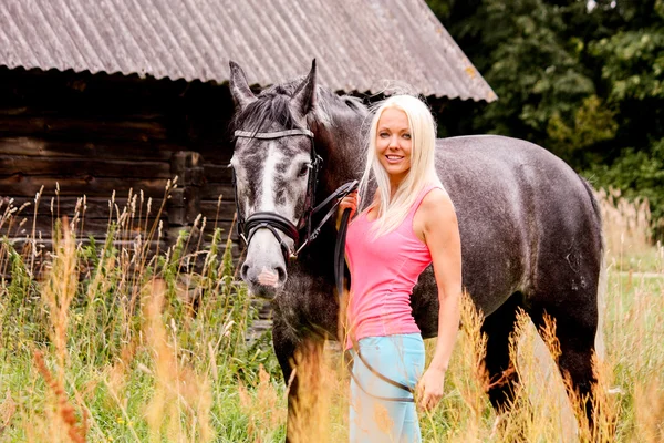 Beautiful blonde woman and her horse in rural area — Stock Photo, Image