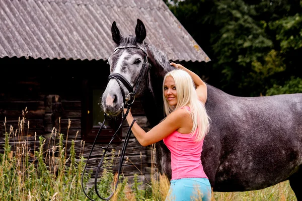 Beautiful blonde woman and her horse in rural area — Stock Photo, Image